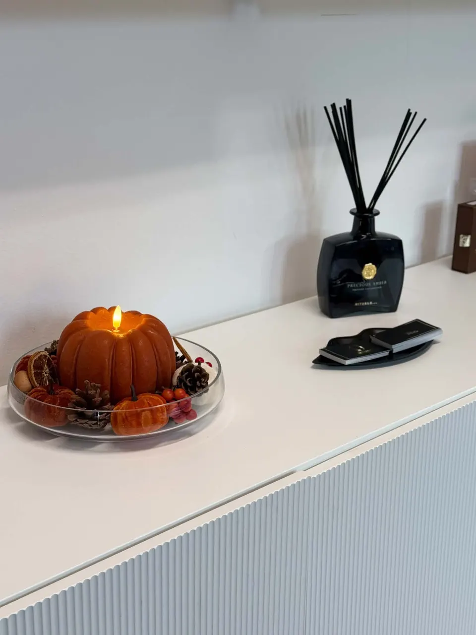 A candle and diffuser on the studio sideboard